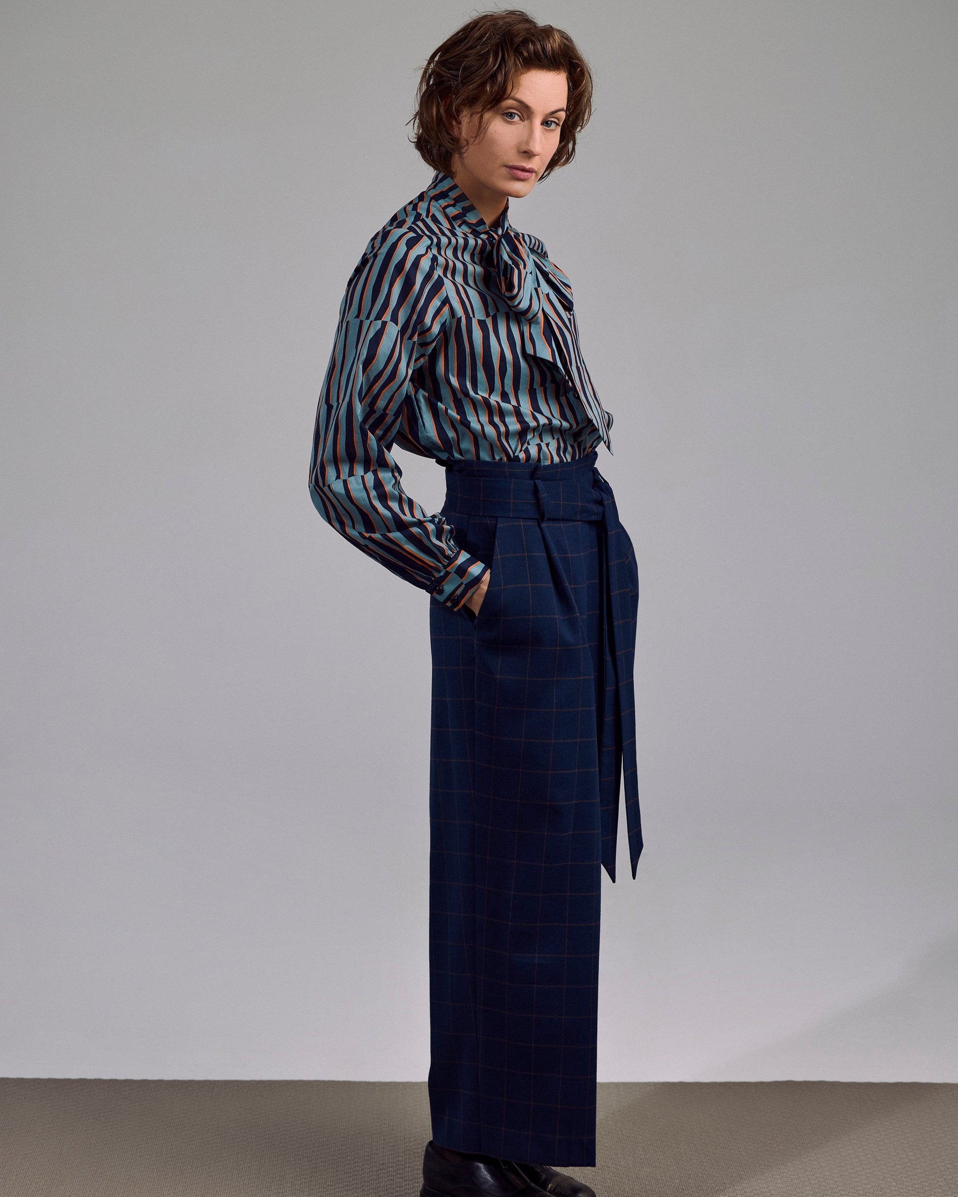 Model trägt die Ovia Bluse in geometrischem Print – kombiniert mit dunkler Hose im urbanen Look