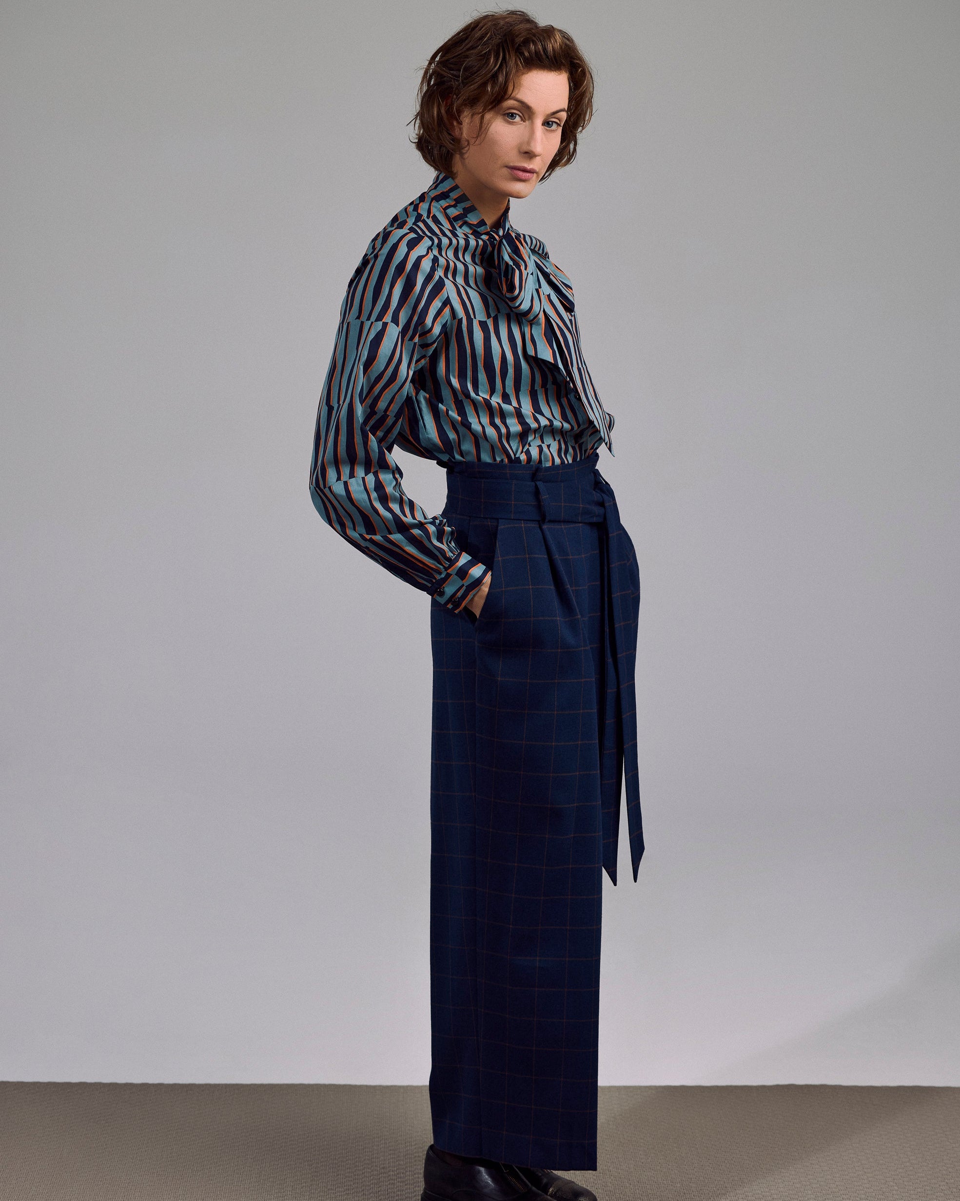 Model trägt die Ovia Bluse in geometrischem Print – kombiniert mit dunkler Hose im urbanen Look