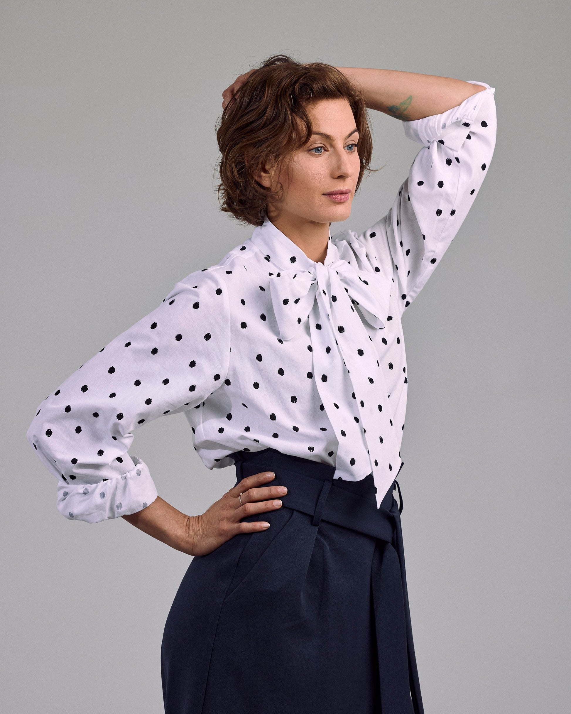Ovia Bluse von Maiken K. mit schwarzen Punkten auf Weiß – frontal getragen mit Schleifen-Detail